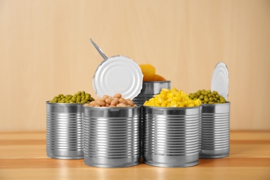 Open tin cans with conserved vegetables and fruits on wooden table