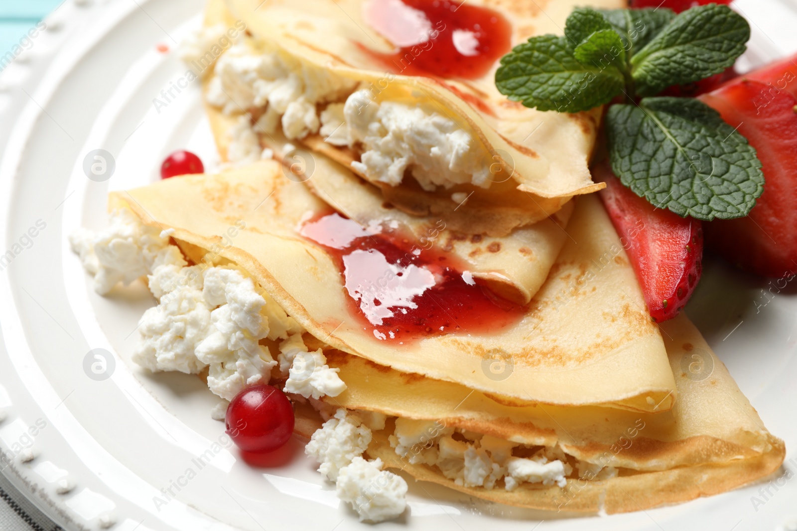 Photo of Delicious thin pancakes with cottage cheese and jam on plate, closeup