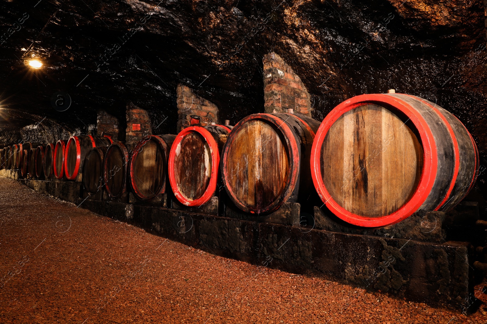 Photo of Many wooden barrels with alcohol drinks in cellar