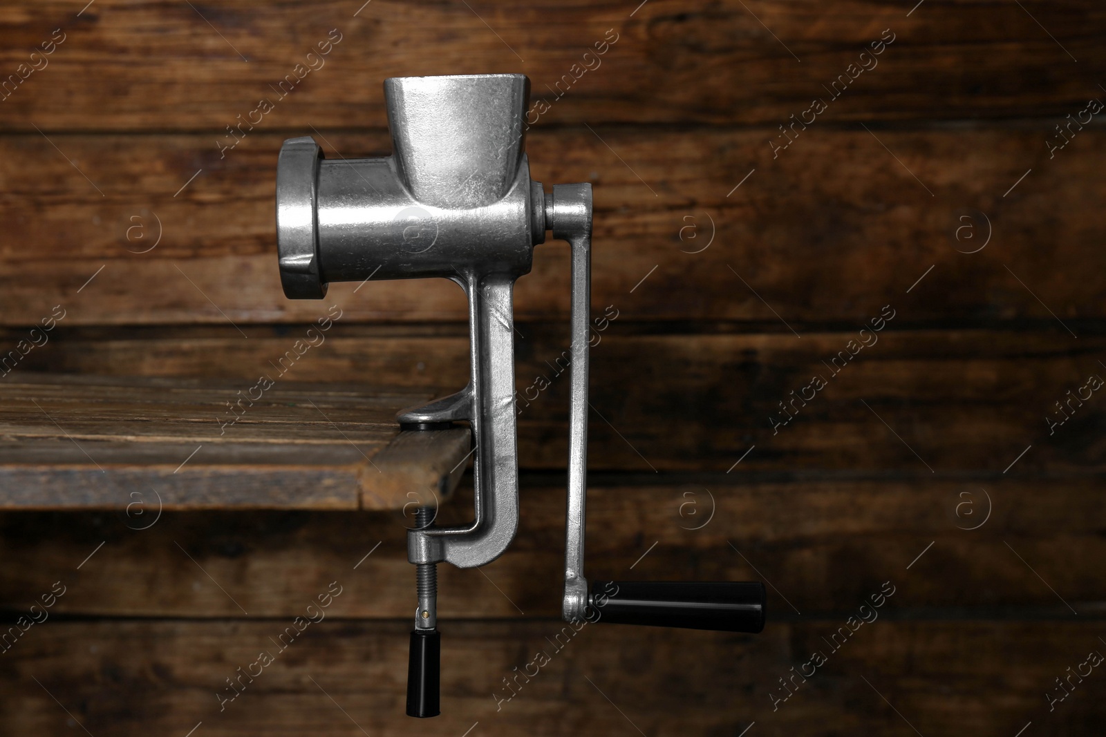 Photo of Metal manual meat grinder on table against wooden background