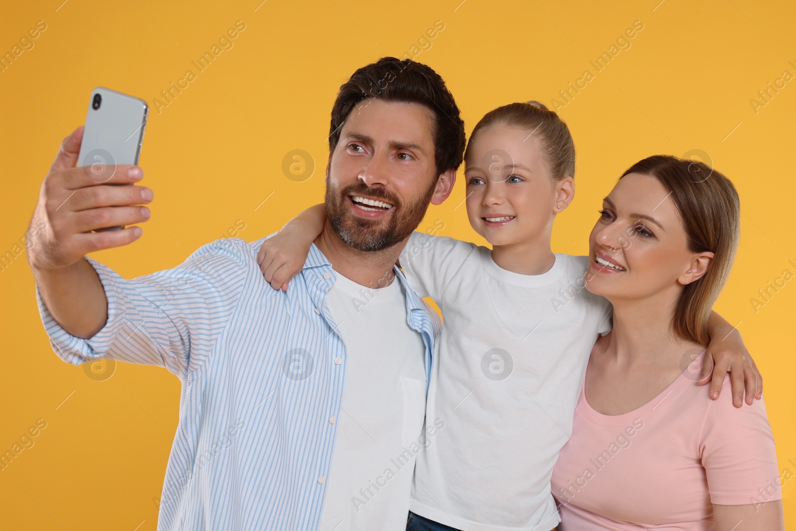 Photo of Happy family taking selfie on orange background