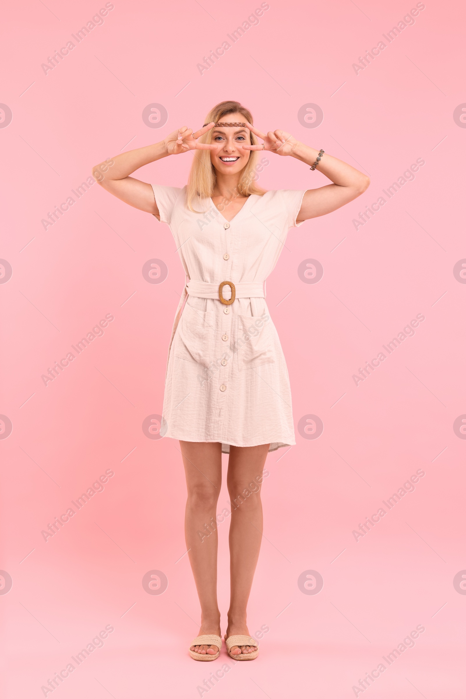 Photo of Beautiful hippie woman showing peace signs on pink background