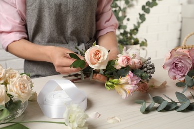 Photo of Florist creating beautiful bouquet at white table indoors, closeup