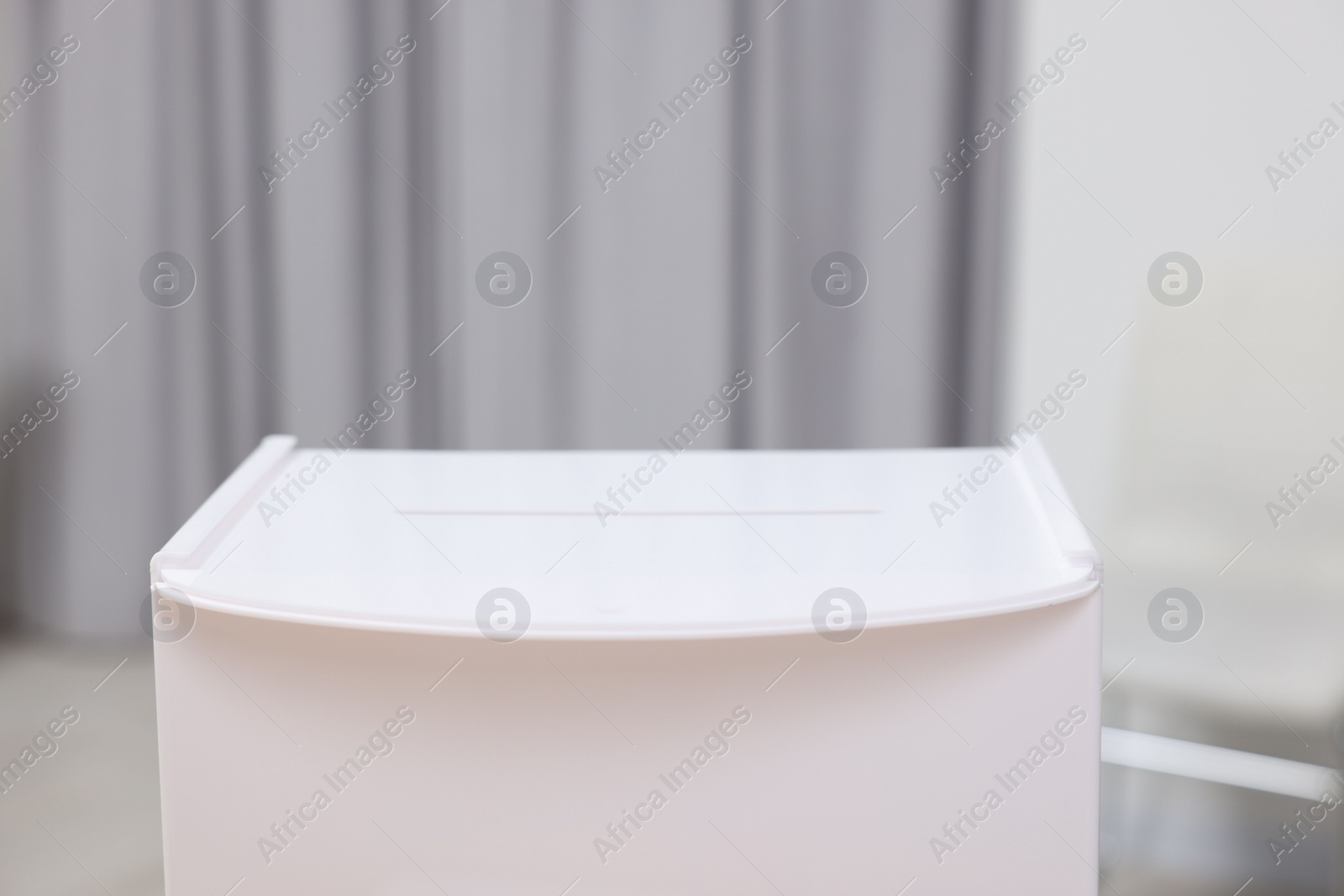 Photo of White ballot box on blurred background, closeup