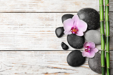 Photo of Stones, bamboo, orchid flowers and space for text on white wooden background, flat lay. Zen lifestyle
