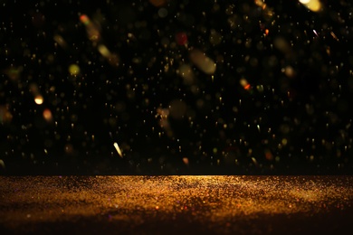 Photo of Golden glitter against black background. Space for text