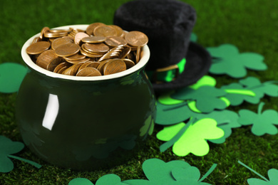 Pot of gold coins and clover leaves on green grass, closeup. St. Patrick's Day celebration