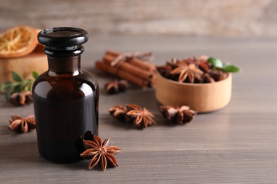 Photo of Anise essential oil and spice on wooden table. Space for text