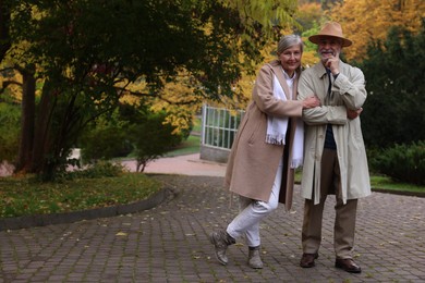 Photo of Affectionate senior couple in autumn park, space for text