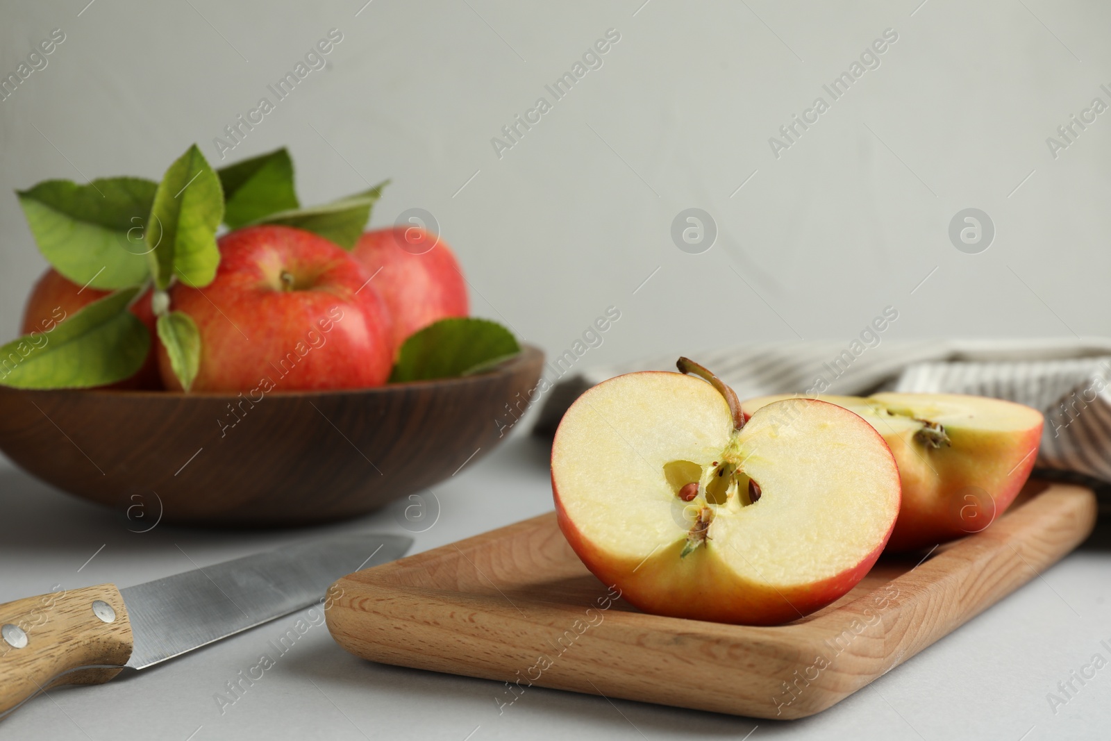 Photo of Whole and cut fresh apples on white table, selective focus. Space for text