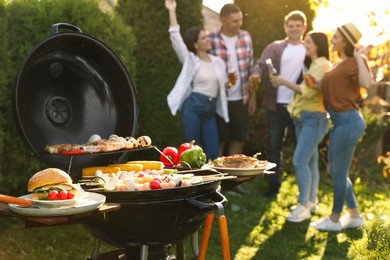 Photo of Group of friends having party outdoors. Focus on barbecue grill with food