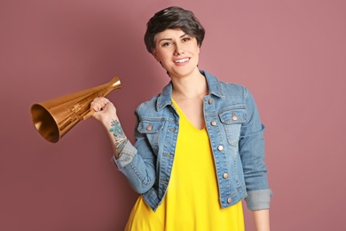 Young woman with megaphone on color background