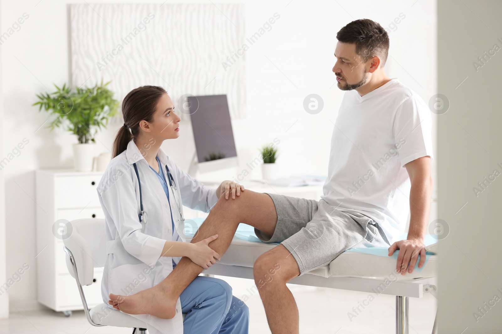 Photo of Female orthopedist examining patient's leg in clinic