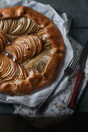 Photo of Delicious apple galette with walnuts, knife and fork on wooden table, flat lay