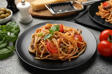 Photo of Delicious pasta with anchovies, tomatoes and olives on grey table