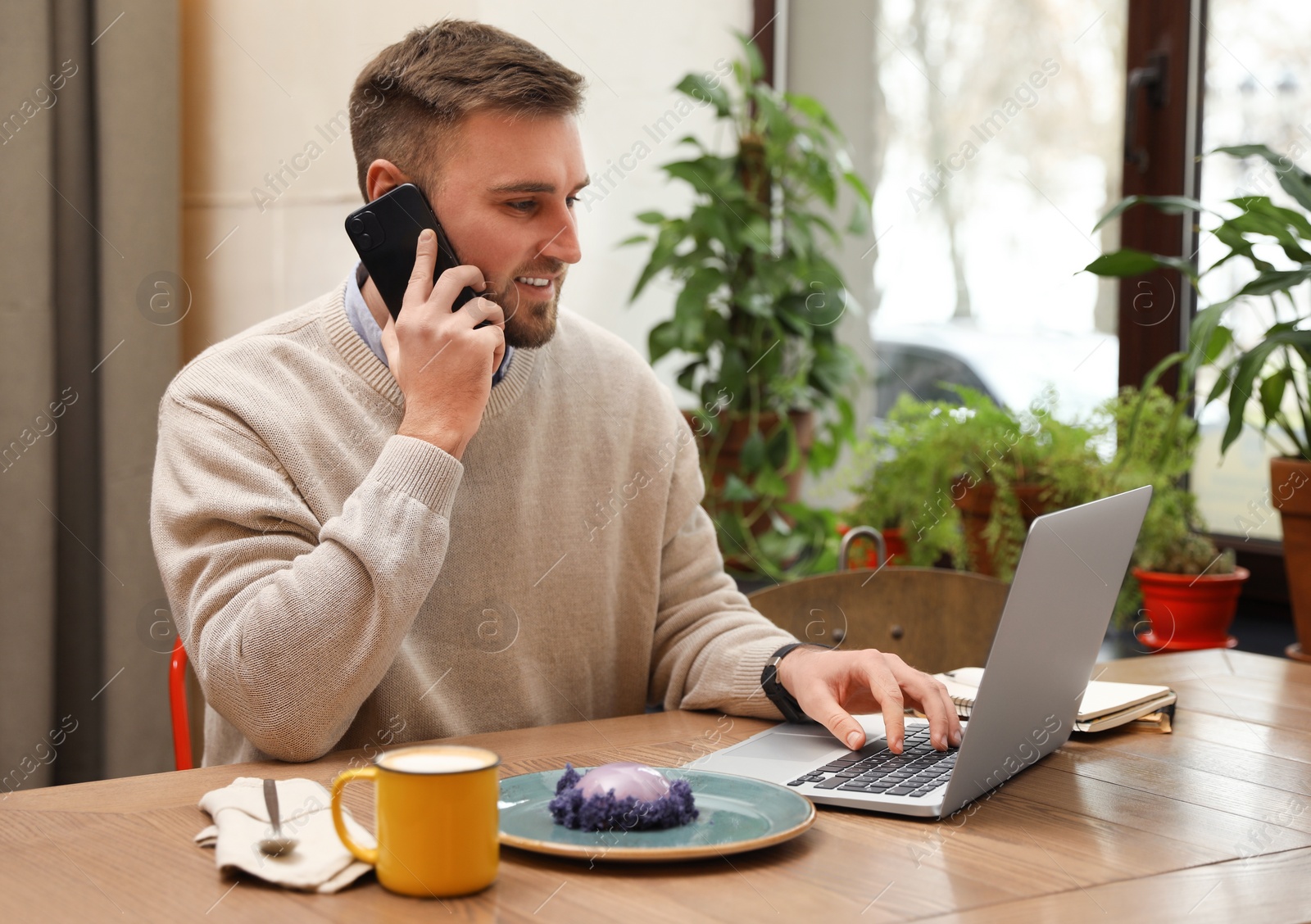 Photo of Male blogger talking on phone in cafe