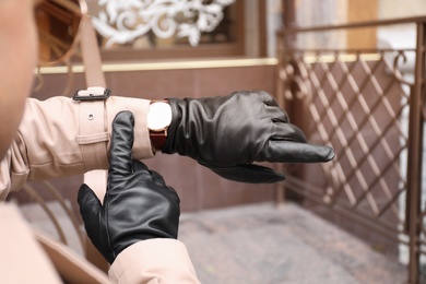Photo of Stylish man in black leather gloves looking at his watch outdoors, closeup