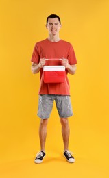 Photo of Man with red cool box on orange background