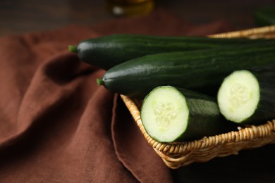 Photo of Fresh cucumbers in wicker basket on table, closeup. Space for text