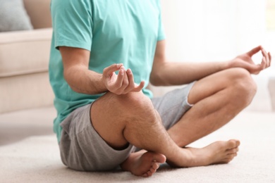 Photo of Man meditating on floor at home, closeup. Zen concept