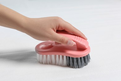 Photo of Woman cleaning white mattress with brush, closeup