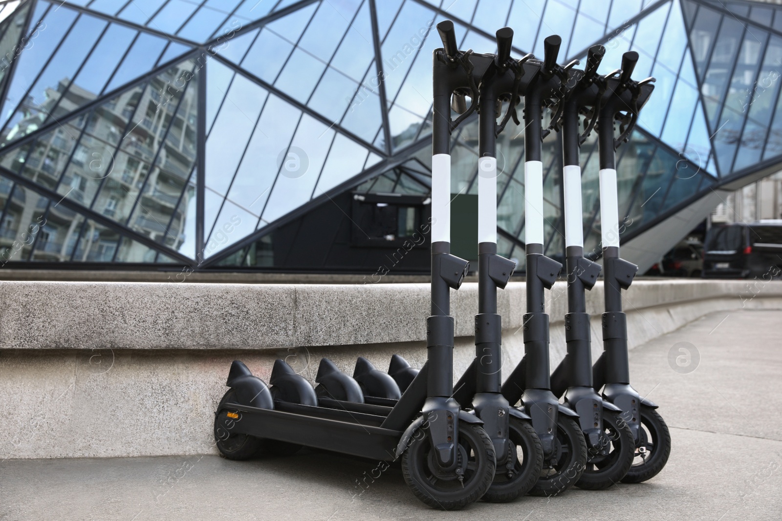 Photo of Row of electric scooters on city street. Rental service