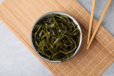 Photo of Tasty seaweed salad in bowl served on gray table, flat lay