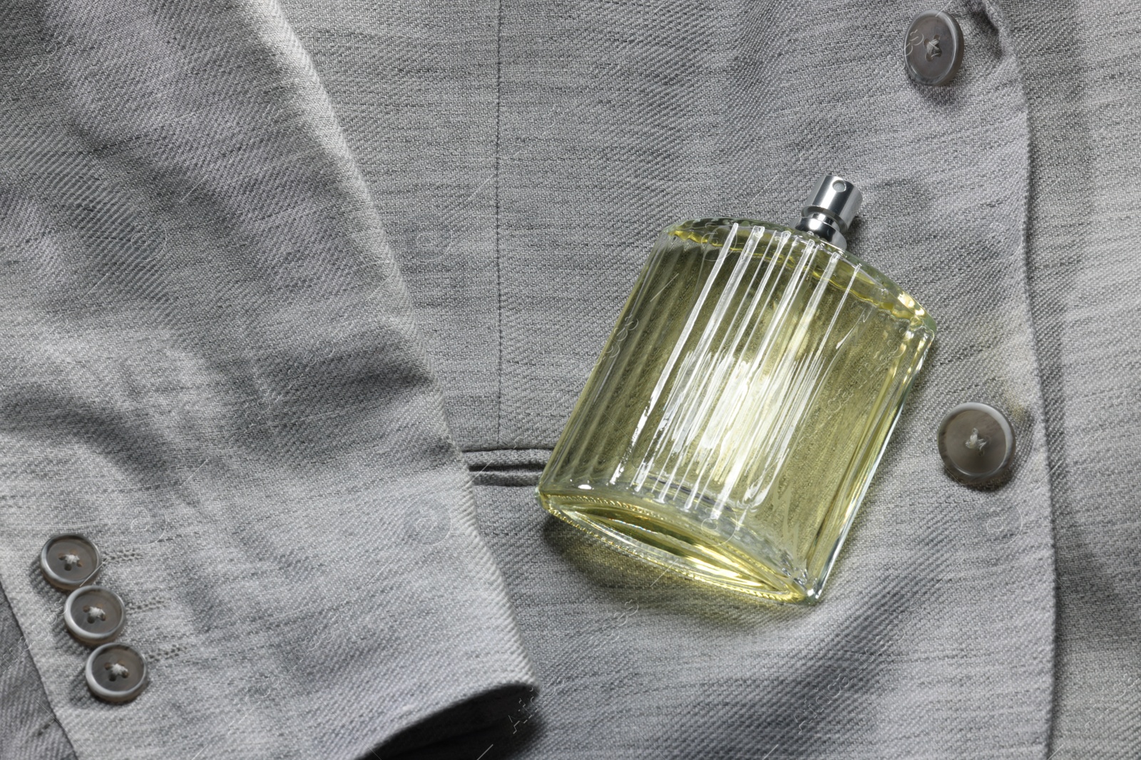 Photo of Luxury men's perfume in bottle on grey jacket, space for text