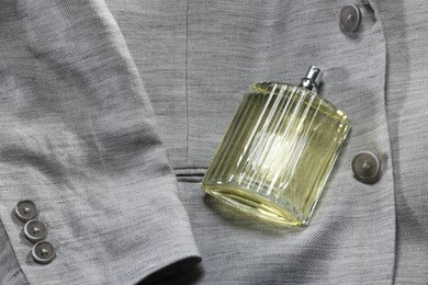 Luxury men's perfume in bottle on grey jacket, space for text