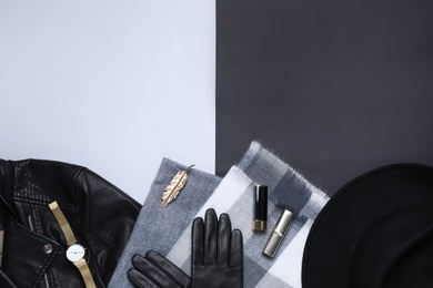 Black leather jacket, scarf and accessories on color background, flat lay. Space for text