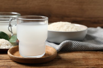 Photo of Glass of rice water on wooden table. Space for text