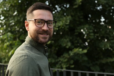 Portrait of handsome bearded man in glasses outdoors, space for text