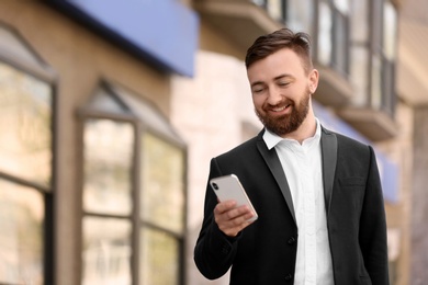 Photo of Portrait of young businessman with smartphone outdoors