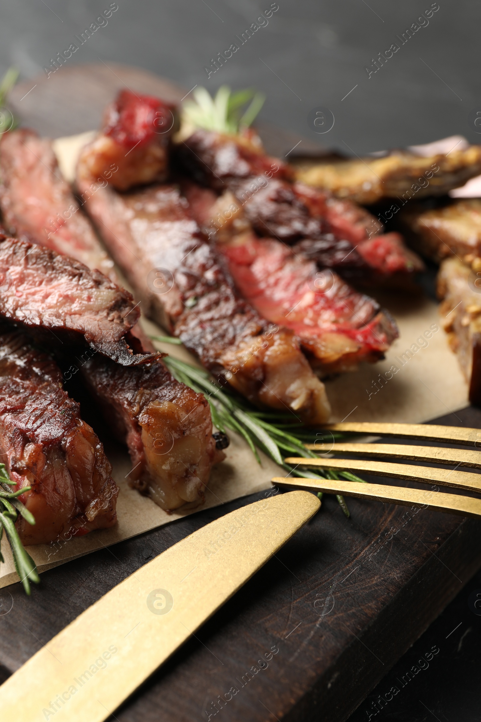 Photo of Delicious grilled beef with rosemary served on wooden board, closeup