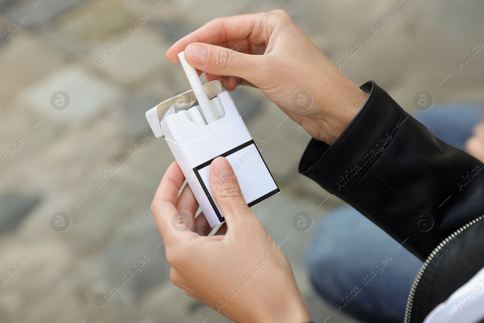 Photo of Woman taking cigarette out of pack outdoors, closeup