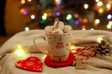 Photo of Cup of delicious hot cocoa with marshmallows and beautiful Christmas decor on white cloth
