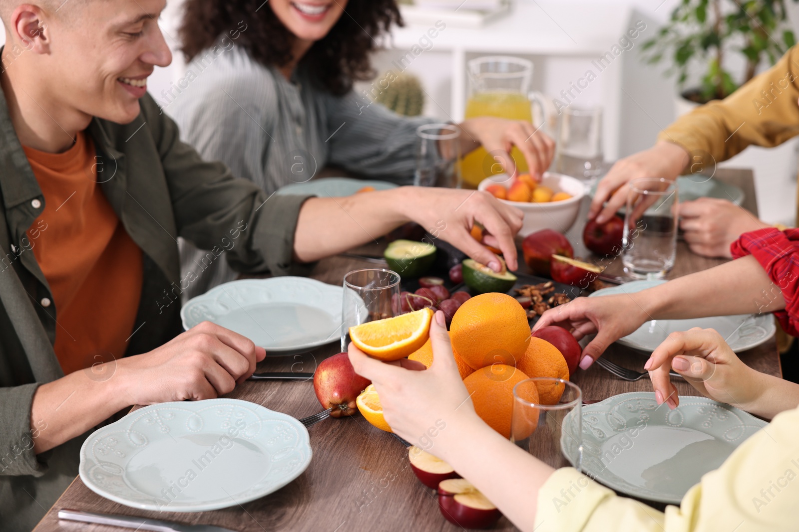 Photo of Friends eating vegetarian food at wooden table indoors