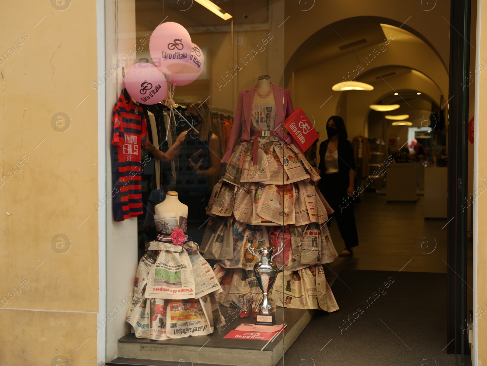 Photo of JESI, ITALY - MAY 17, 2022: Beautiful dresses made of newspapers in boutique, view from outside