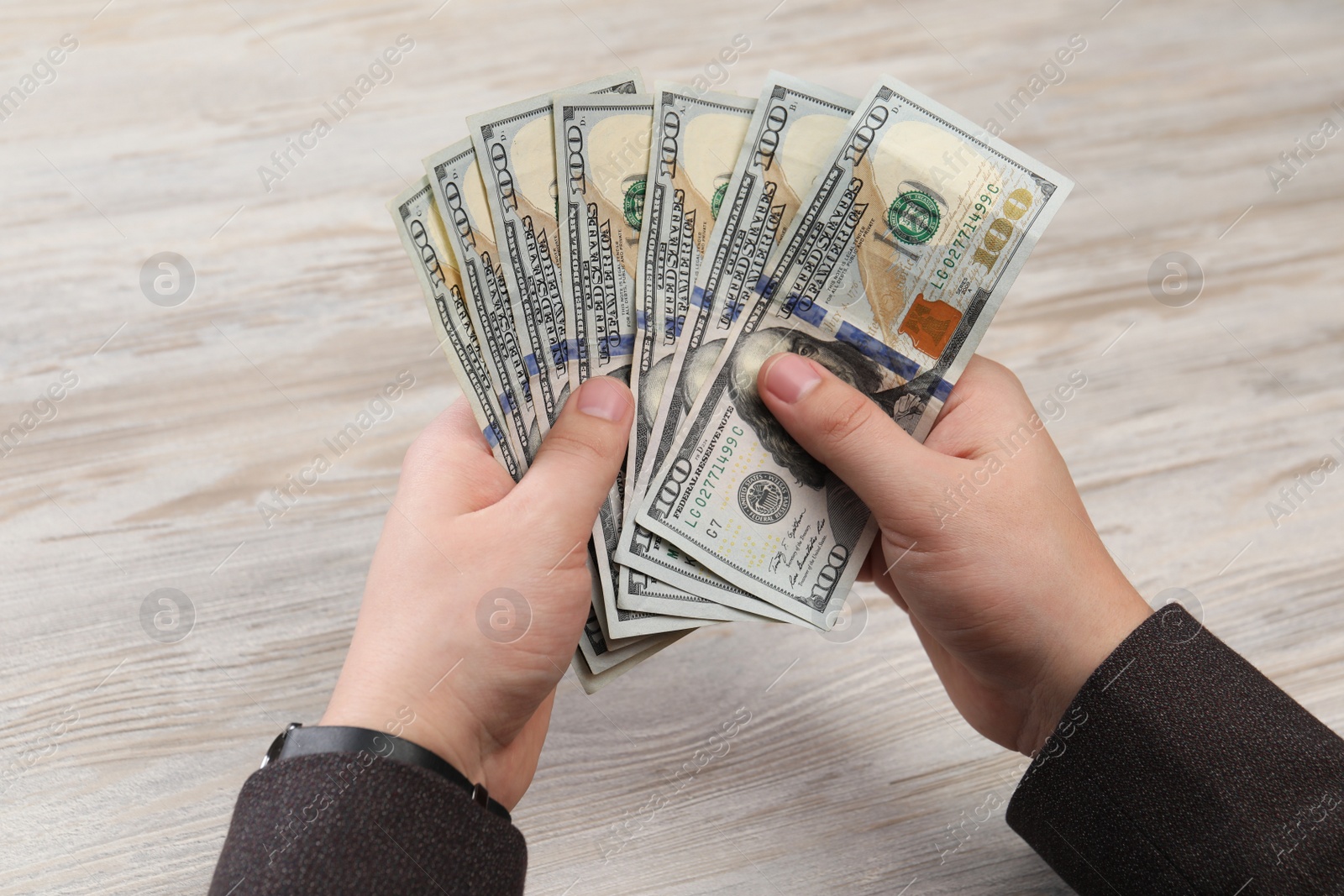 Photo of Man counting money at white wooden table, closeup. Currency exchange