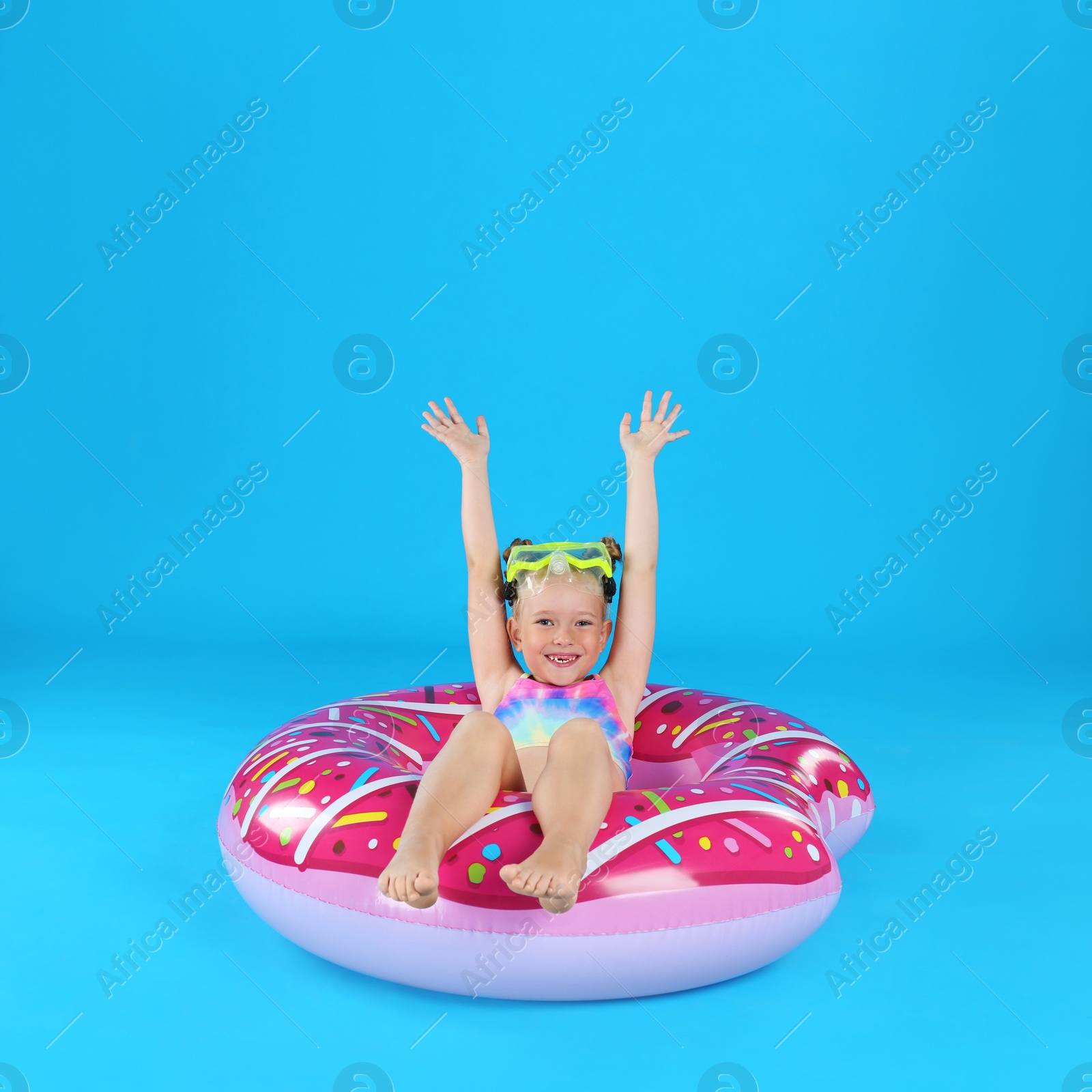 Photo of Cute little child in beachwear with inflatable ring on light blue background