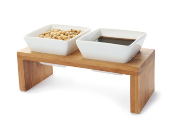 Photo of Wooden stand with dishes of soy sauce and beans on white background