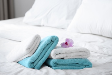Photo of Clean towels and pink orchid on bed
