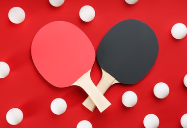 Photo of Ping pong rackets and balls on red background, flat lay