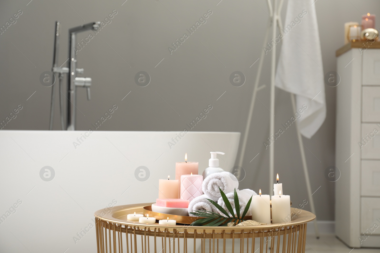 Photo of Stylish bathroom interior with ceramic tub and spa products on table