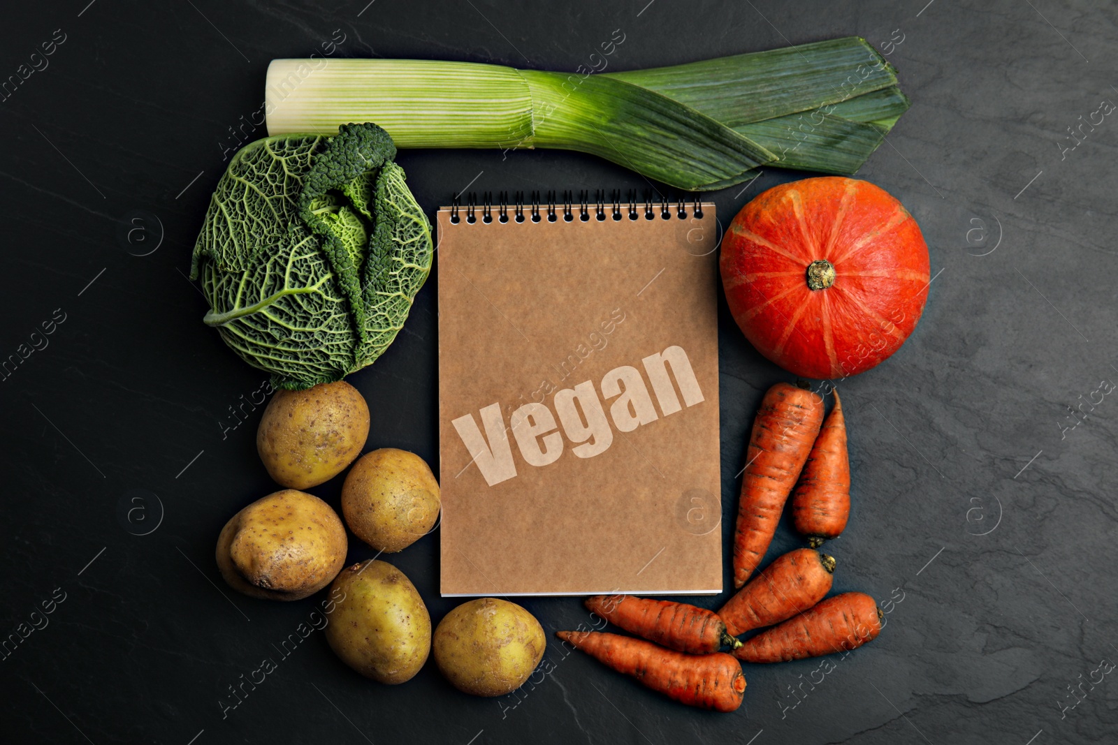 Image of Notebook with word Vegan and fresh vegetables on black background, flat lay