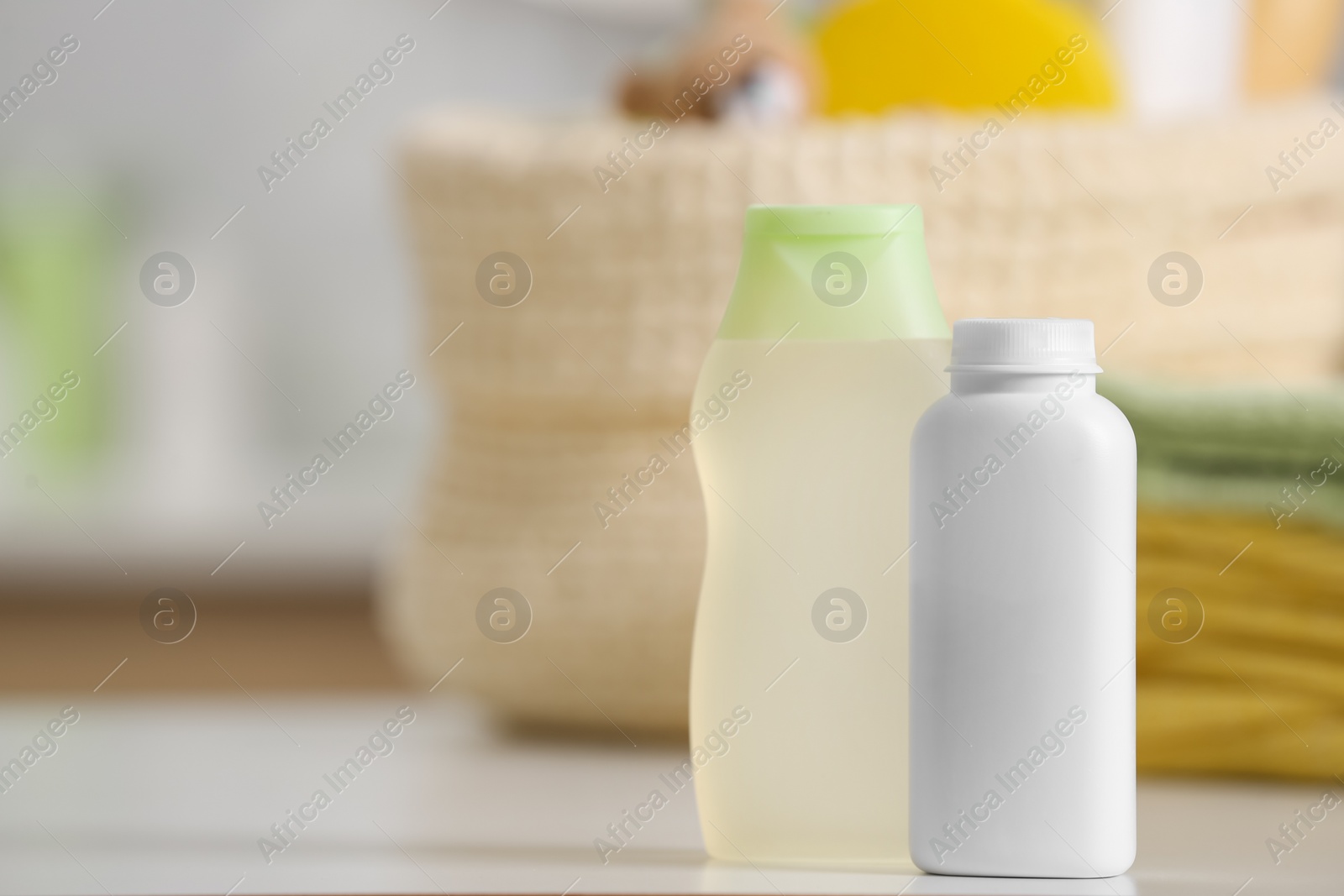 Photo of Bottles of baby cosmetic products and towels on white table, space for text