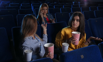 Rude woman talking on phone and disturbing other viewers in cinema