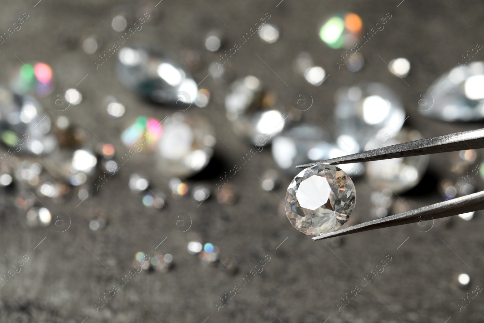 Photo of Tweezers with beautiful gemstone on blurred background. Space for text