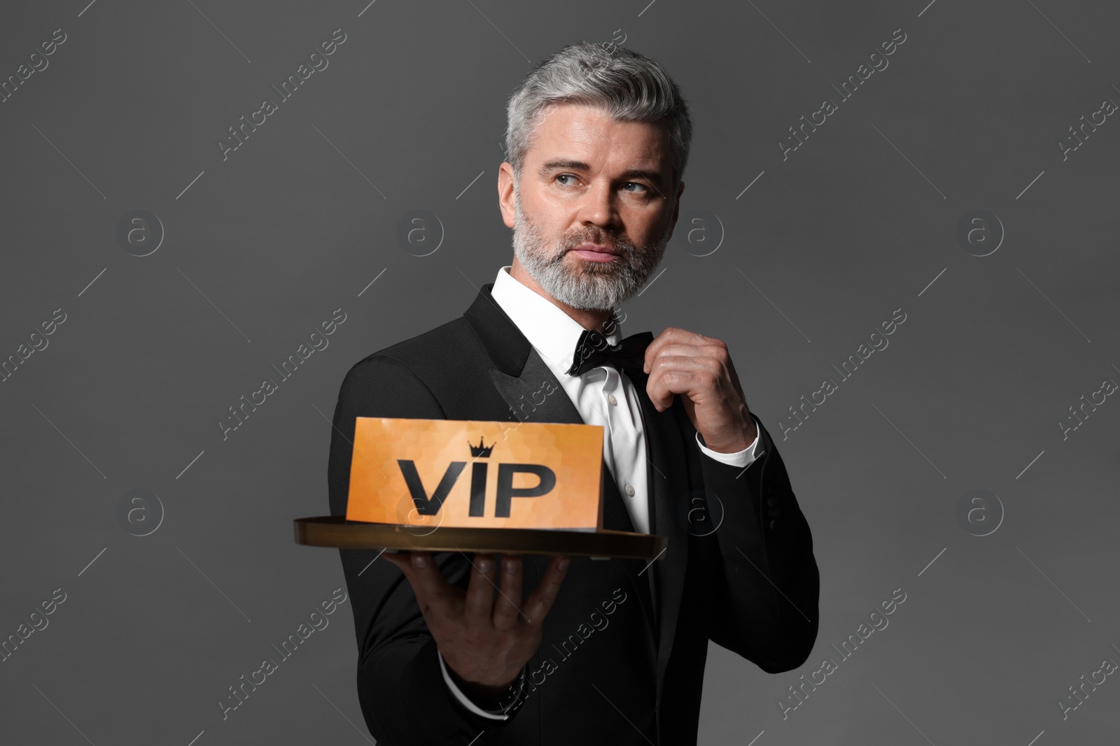 Photo of Handsome man holding tray with VIP sign on grey background