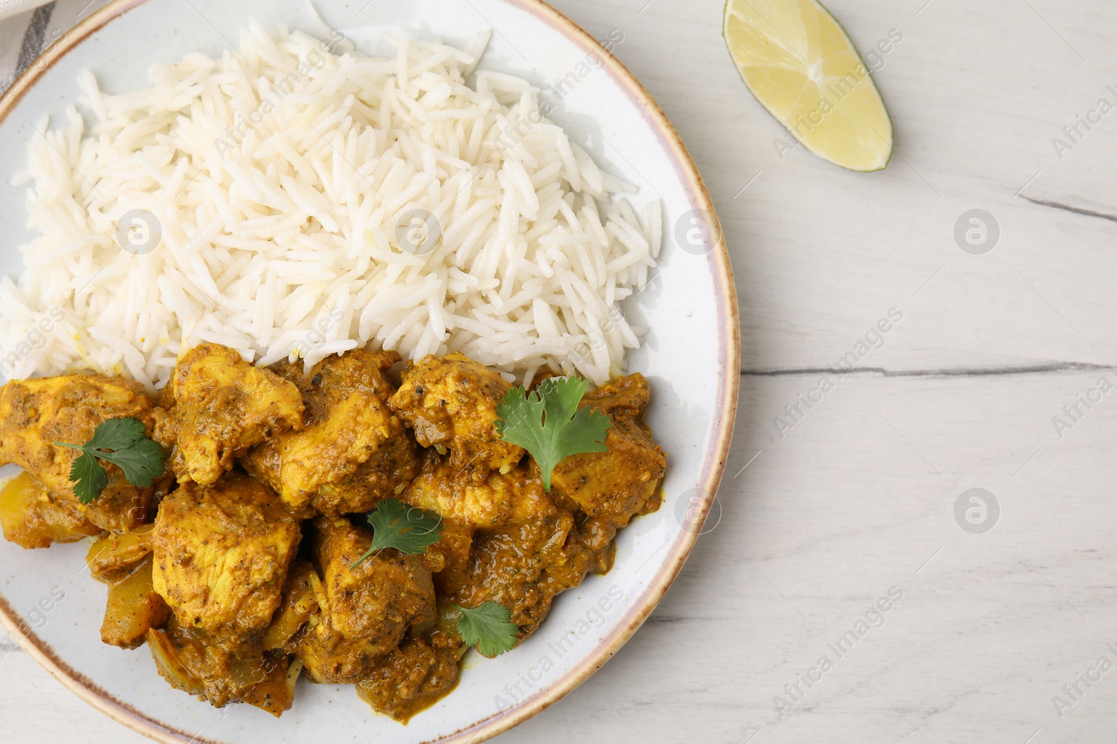 Photo of Delicious chicken curry with rice on white wooden table, top view